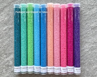 Peut inclure: Une collection de perles de rocaille dans des tubes transparents, disposées en rangée. Les perles sont de différentes couleurs, dont le turquoise, le vert, le bleu, le pêche, le rose, le magenta et le violet. Chaque tube porte l'inscription "Size 11". Le texte "Packaged and Shipped in Tubes" est visible.