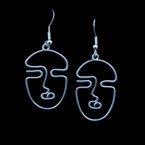 Bijou lumineux : boucles d’oreilles en fil doré éclairé dans l’obscurité, mettant en avant un design audacieux et moderne.