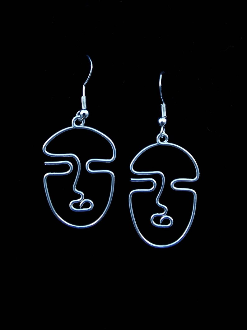 Bijou lumineux : boucles d’oreilles en fil doré éclairé dans l’obscurité, mettant en avant un design audacieux et moderne.
