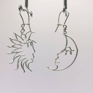 Boucles d’oreilles pendantes avec un design solaire et lunaire, faites à la main en fil métallique doré. Un bijou intemporel aux lignes épurées et artistiques.