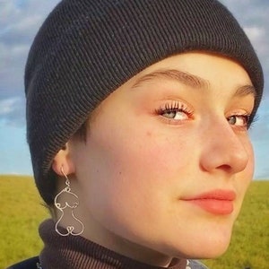 Paire de boucles d’oreilles élégantes et artistiques en fil de métal doré, inspirées de l’anatomie féminine.