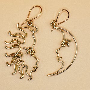 Gros plan sur les boucles d’oreilles Soleil et Lune en acier inoxydable doré, mettant en valeur les détails fins du fil torsadé et la finesse du travail artisanal.