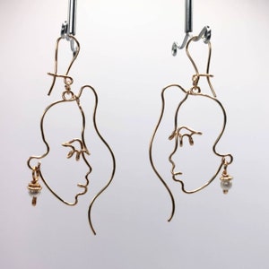Boucles d&#39;oreilles visage, abstraction en fil d&#39;or en une seule ligne.