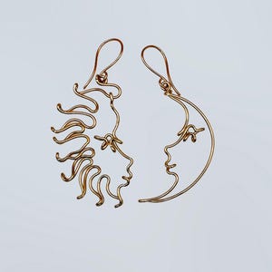 Boucles d’oreilles asymétriques représentant le soleil et la lune, réalisées à la main en fil doré. Un bijou unique au design céleste, parfait pour un look mystique et élégant.