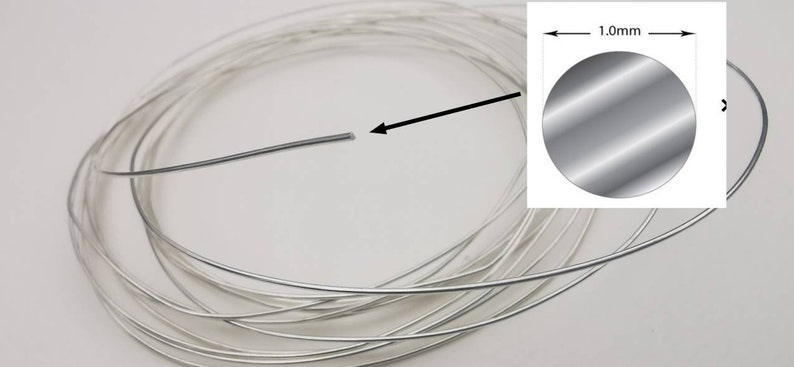 May include: A coil of silver wire, 1.0 mm in diameter. The wire is coiled and ready for use in jewelry making or other crafts.