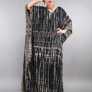 May include: A black and brown tie-dye kaftan with a V-neckline. The kaftan has a long, flowing silhouette and is made of a soft, comfortable fabric.