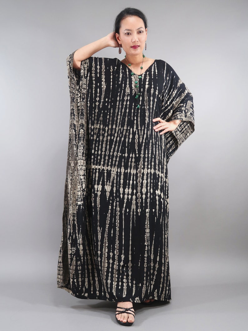 May include: A black and brown tie-dye kaftan with a V-neckline. The kaftan has a long, flowing silhouette and is made of a soft, comfortable fabric.