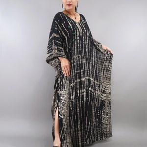 May include: A long black and silver tie-dye maxi dress with a V-neck and long sleeves. The dress has a side slit and is made of a soft, flowing fabric.