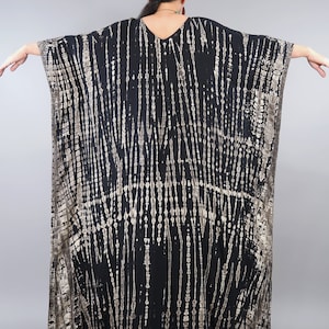 May include: Black and gold tie-dye kaftan with a V-neckline. The kaftan has a flowing, loose fit and is made of a soft, comfortable fabric.
