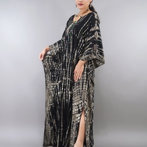 May include: A long black and brown tie-dye kaftan with a side slit. The kaftan has a loose, flowing fit and is made of a soft, comfortable fabric.