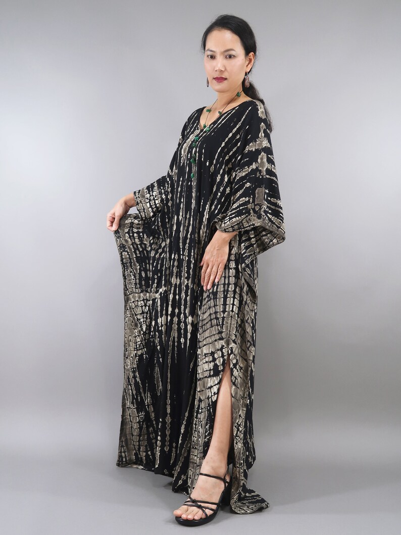 May include: A long black and brown tie-dye kaftan with a side slit. The kaftan has a loose, flowing fit and is made of a soft, comfortable fabric.