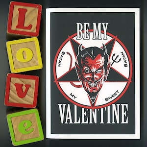 Puede incluir: Una tarjeta en blanco y negro con un pentagrama rojo y un diablo rojo con cuernos y cola. El texto en la tarjeta dice "Be My Sweet Satan Valentine".