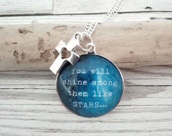 Può includere: Una collana d'argento con un ciondolo di vetro blu che dice "You will shine among them like stars..." e un ciondolo a croce d'argento.