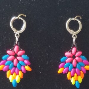 May include: A pair of dangle earrings with a silver hoop and a colorful beaded design. The beads are arranged in a flower shape with pink, blue, orange, and yellow beads.