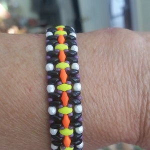 May include: A black, white, orange, yellow, and purple beaded bracelet. The bracelet is made with small, round beads.