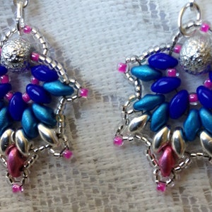 May include: A pair of star-shaped earrings with silver, blue, and pink beads. The earrings are made with small, oval-shaped beads.
