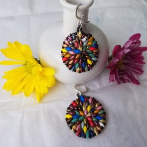 May include: A pair of colorful beaded earrings with a circular design. The earrings are made with small, multi-colored beads and have silver hooks.
