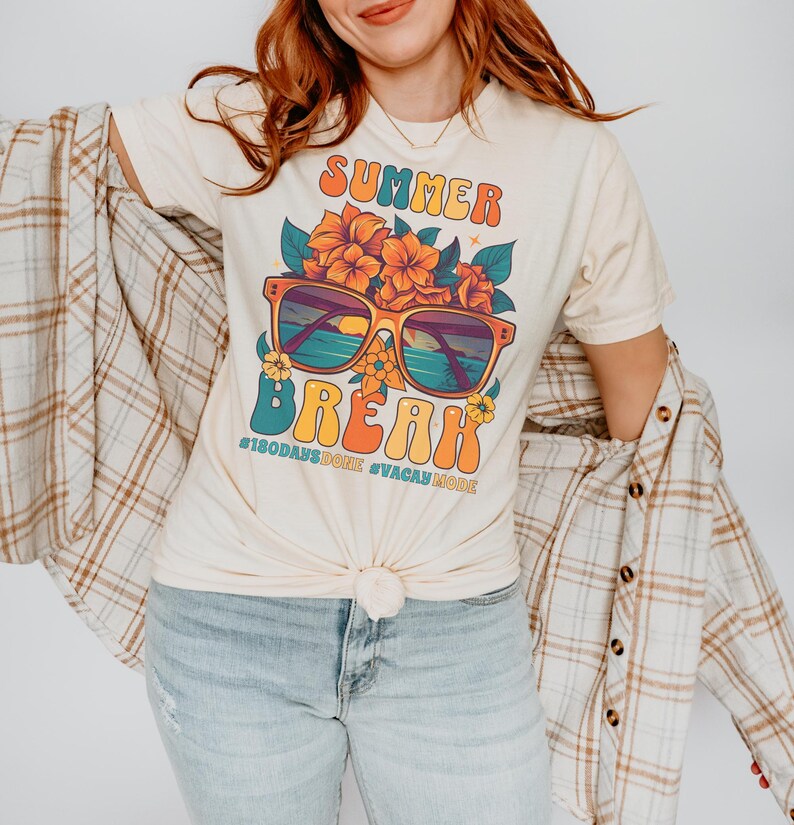 May include: A light beige t-shirt with a retro-style graphic design featuring sunglasses, flowers, and the text "Summer Break #180daysdone #vacaymode".