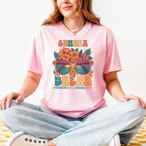 May include: Pink t-shirt with a retro graphic design featuring sunglasses, flowers, and the text "Summer Break" with the hashtags "#180days" and "#vacaymode".