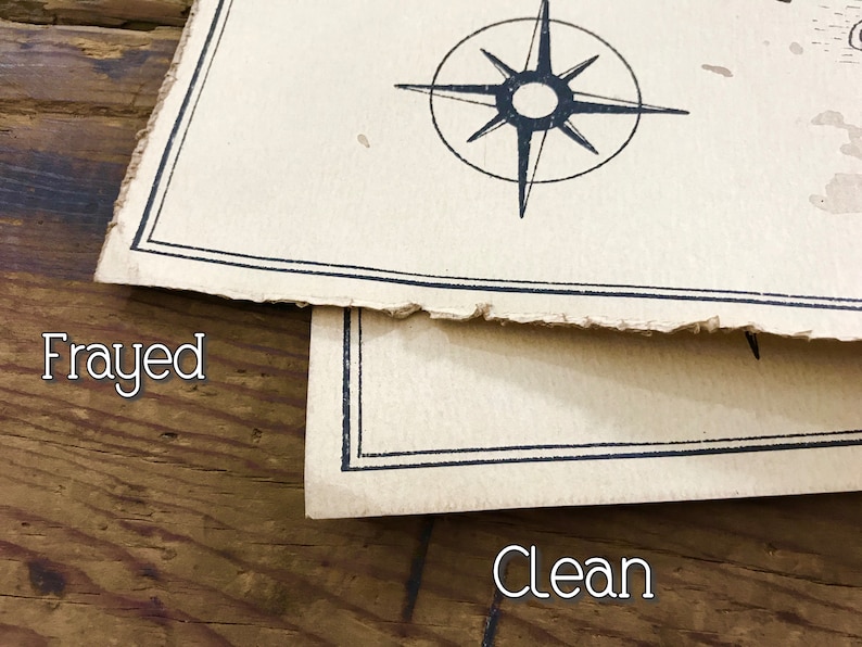 A close up of two maps resting on top of each other to show the corners and the edges. The map on top has frayed edges, while the map below has clean edges. Both are resting on a brown wooden surface.