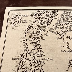 A close up of the details of the map, including the ocean, trees, and mountains.