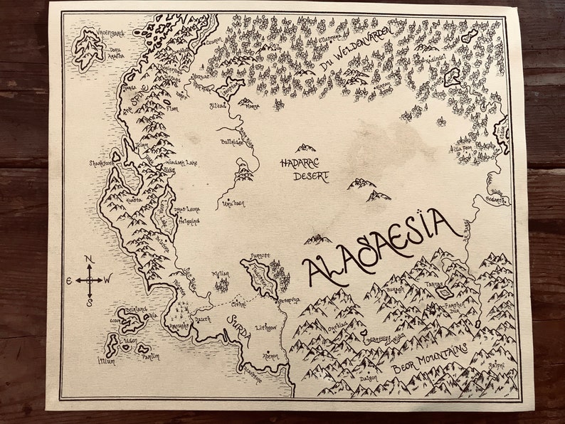 An overall picture of the map of Alagaesia, showing the hand-drawn details and writing. The paper is stained brown and the writing is black. The map is resting on a dark brown wooden surface.