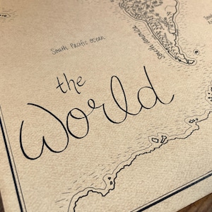 May include: A tan-colored world map print on textured paper featuring black ink line drawings of coastlines and landmasses. The text "the World" is written in a large, cursive script, with "South Pacific ocean" and "South America" labels.
