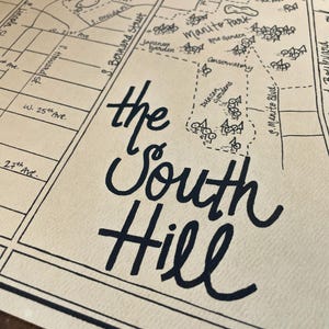 May include: A hand-drawn map on cream-colored paper featuring black ink lines and lettering. The map displays street names like Lincoln Street and S. Bernard Street, and landmarks including Manito Park, the Japanese Garden, and the Conservatory.