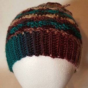 May include: A crocheted beanie hat with a multi-colored striped pattern in shades of brown, teal, and beige.