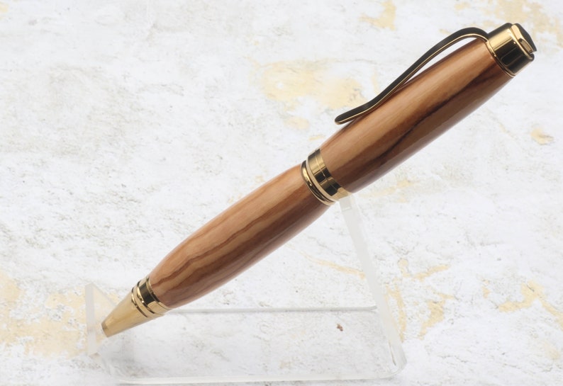 Side view in clear pen stand of Titanium Gold Cigar Pen made with olive wood and gold hardware