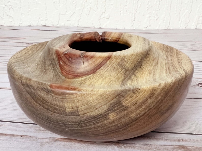 Camphor wood bowl - close-up showing curved grain pattern and multiple colors, including the red-brown knot at the top of the bowl