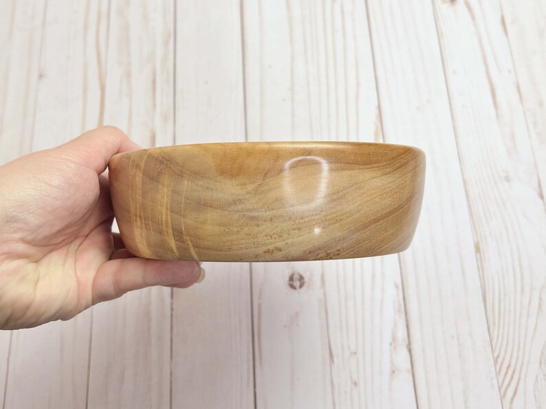 Shallow bowl made from camphor wood - being held to show side view