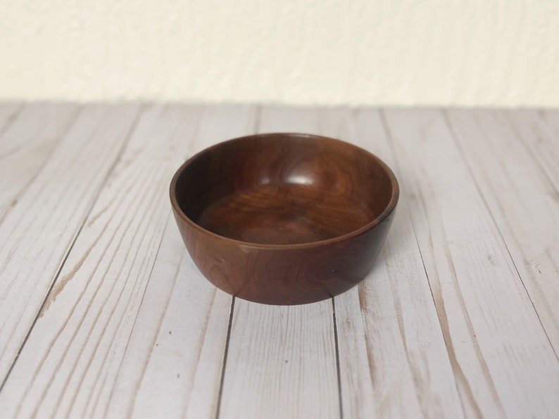 Indian Rosewood wooden bowl on woodgrain table - angled view showing more of the inside of the bowl