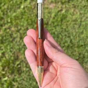 Holding the eucalyptus wood 2mm mechanical pencil in natural light to show off the reddish brown of the wood and the gold hardware.