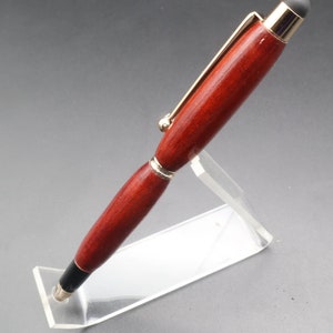 View of pen tip for Bloodwood stylus pen with gold hardware on clear pen stand over black background