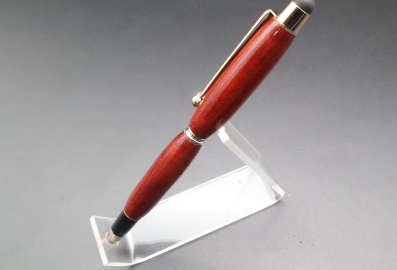 View of pen tip for Bloodwood stylus pen with gold hardware on clear pen stand over black background