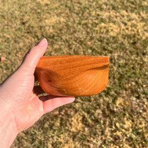 Osage Orange wooden bowl with square top and round opening and bowl - being held in natural light, side view