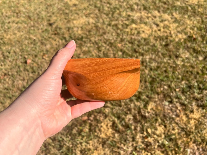 Osage Orange wooden bowl with square top and round opening and bowl - being held in natural light, side view