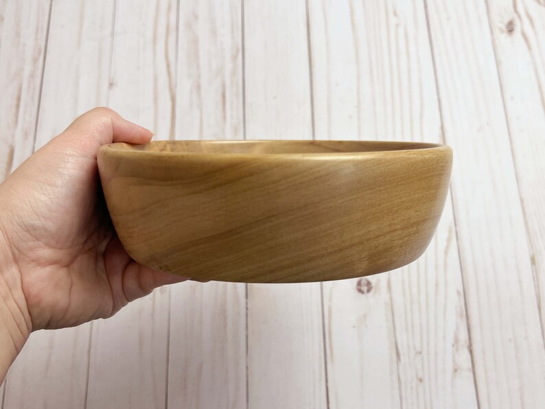 Shallow bowl made from camphor wood - being held to show another side view