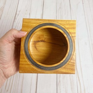 Osage Orange wooden bowl with square top and round opening and bowl - being held so you can look into the bowl