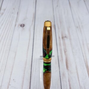 Close view of top of olive wood and resin twist pen with satin gold hardware