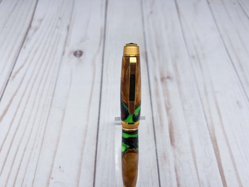 Close view of top of olive wood and resin twist pen with satin gold hardware
