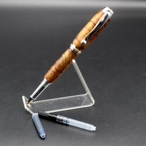 View of pen with cap off and ink refill for Fountain pen made with gold and black maple burl and chrome and gold hardware on clear pen stand over black background