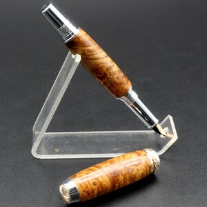 View of pen with cap off for Fountain pen made with gold and black maple burl and chrome and gold hardware on clear pen stand over black background