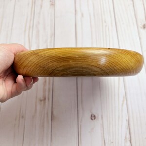 Shallow bowl made of Cypress wood being held - side view