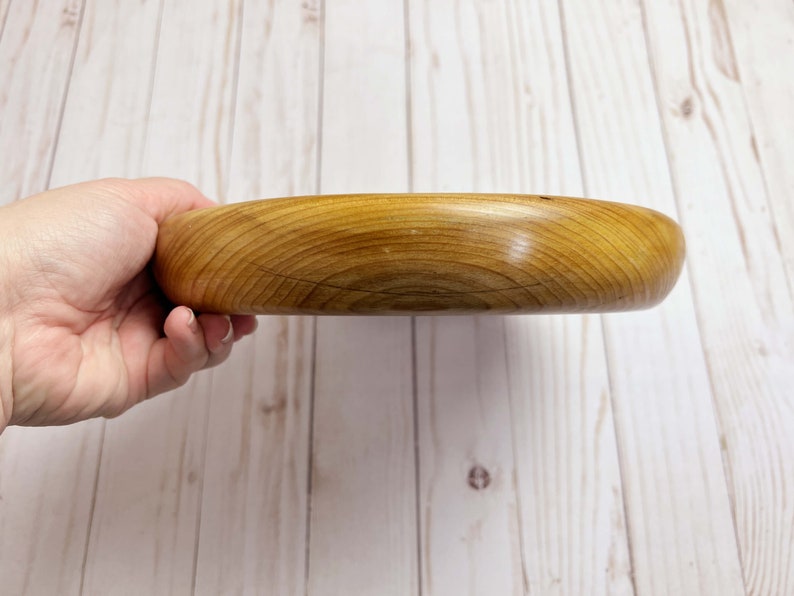 Shallow bowl made of Cypress wood being held - side view