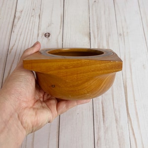 Osage Orange wooden bowl with square top and round opening and bowl - bowl being held so you can see the side with the square top and round bottom