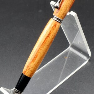 Close-up view of the barrel of the Canarywood stylus pen with gun metal hardware in pen stand over black background