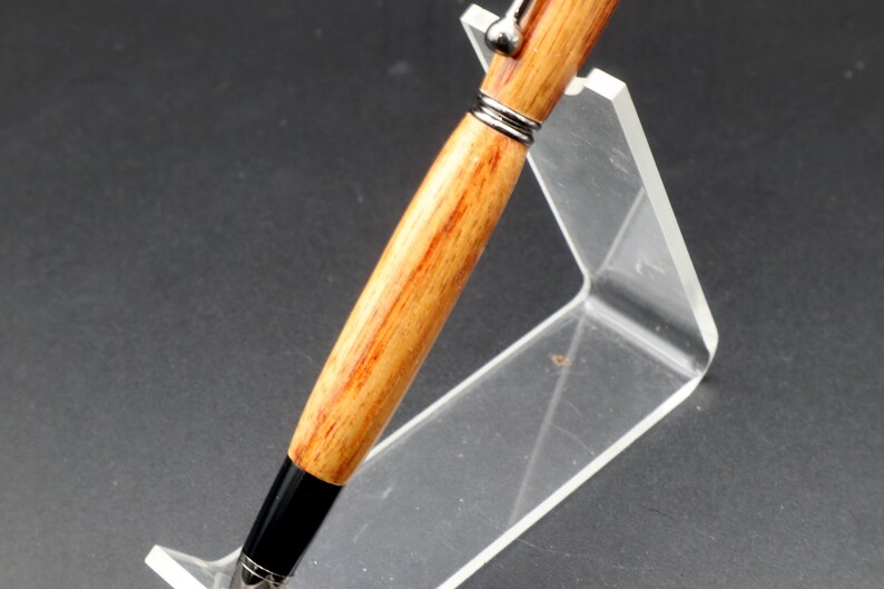 Close-up view of the barrel of the Canarywood stylus pen with gun metal hardware in pen stand over black background