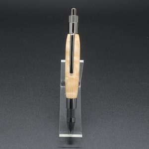 Full front view of click pen made with birds eye maple wood and black hardware. It's in a clear pen stand on a dark background. Maple wood is a light, cream-colored wood with darker brown swirls in the grain.